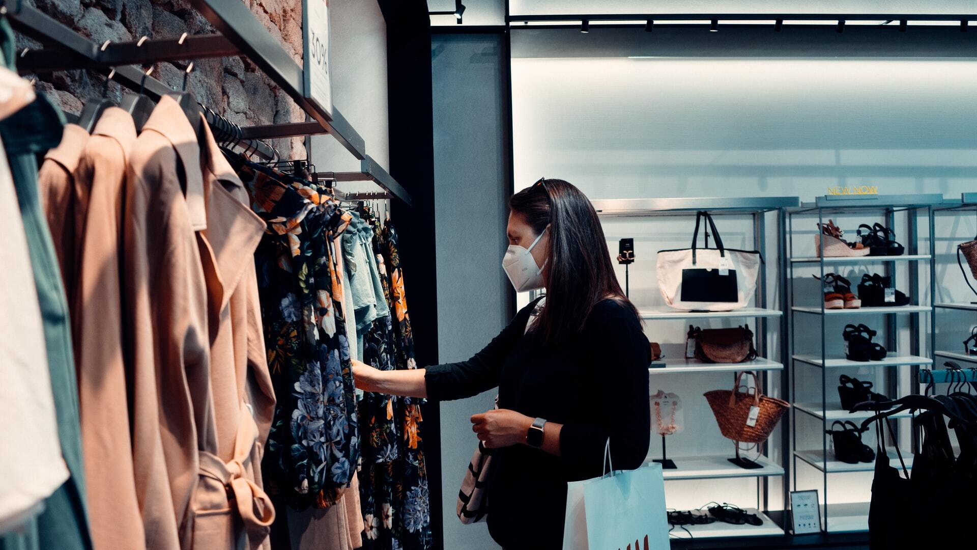 woman shops in clothing store with mask during covid